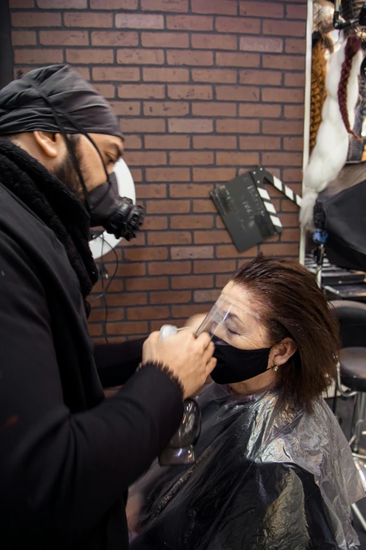 a man cutting a woman's hair in a salon, an airbrush painting, reddit, wearing all black mempo mask, face is wrapped in a black scarf, shot with sony alpha 1 camera, dreadlock black hair