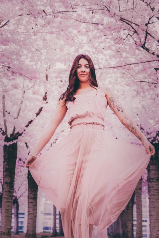 a woman in a pink dress standing under a tree, a colorized photo, inspired by Elsa Bleda, pexels contest winner, falling cherry blossom pedals, soft devil queen madison beer, having a good time, joanna gaines