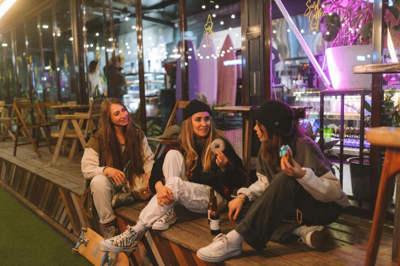 a group of women sitting on top of a wooden bench, trending on pexels, nightlife, small hipster coffee shop, federation clothing, teenage no