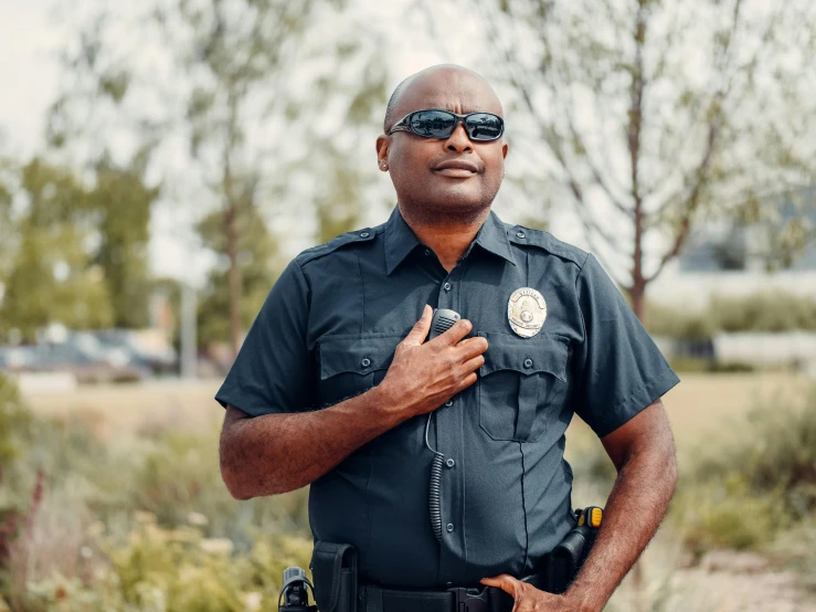 a man in a police uniform posing for a picture, by Carey Morris, unsplash, symbolism, portrait image, wearing shades, schools, diverse