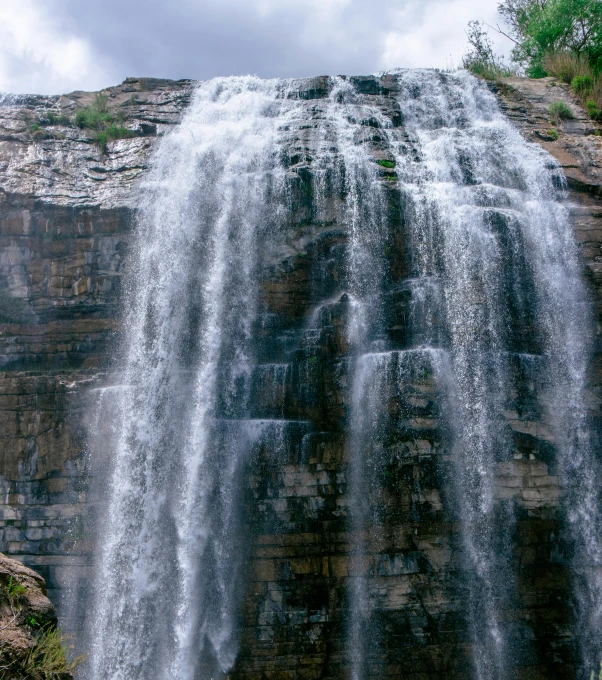 a man standing in front of a waterfall, an album cover, by Kristin Nelson, pexels contest winner, hurufiyya, panoramic, minn, today\'s featured photograph 4k, waterfall flowing from the stone