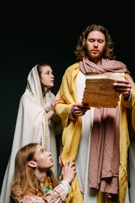 a group of people dressed as jesus and mary, inspired by Moses van Uyttenbroeck, unsplash, renaissance, he is holding a large book, studio lit, ( ( theatrical ) ), reading
