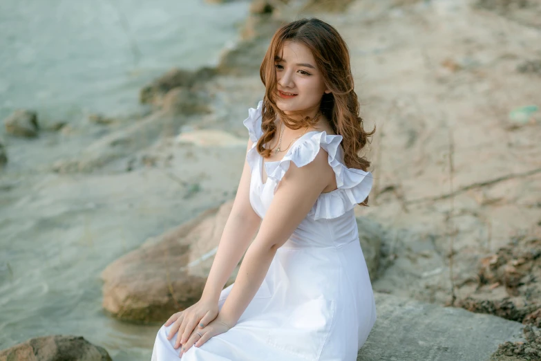 a woman in a white dress sitting on a rock, inspired by Kim Du-ryang, pexels contest winner, girl cute-fine-face, bbwchan, 2 2 years old, video