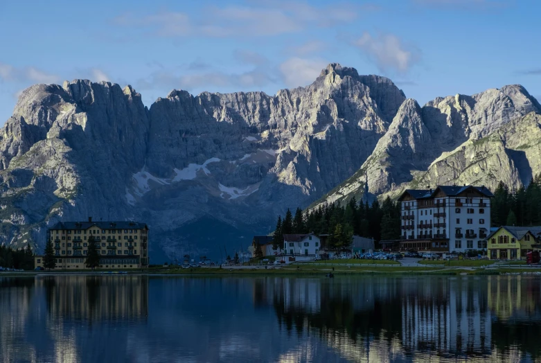 a large body of water with mountains in the background, by Carlo Martini, pexels contest winner, lago di sorapis, buildings carved out of stone, late morning, fan favorite