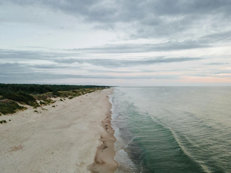 a large body of water next to a sandy beach, by Daniel Lieske, unsplash contest winner, hammershøi, flying over the horizon, late summer evening, john pawson