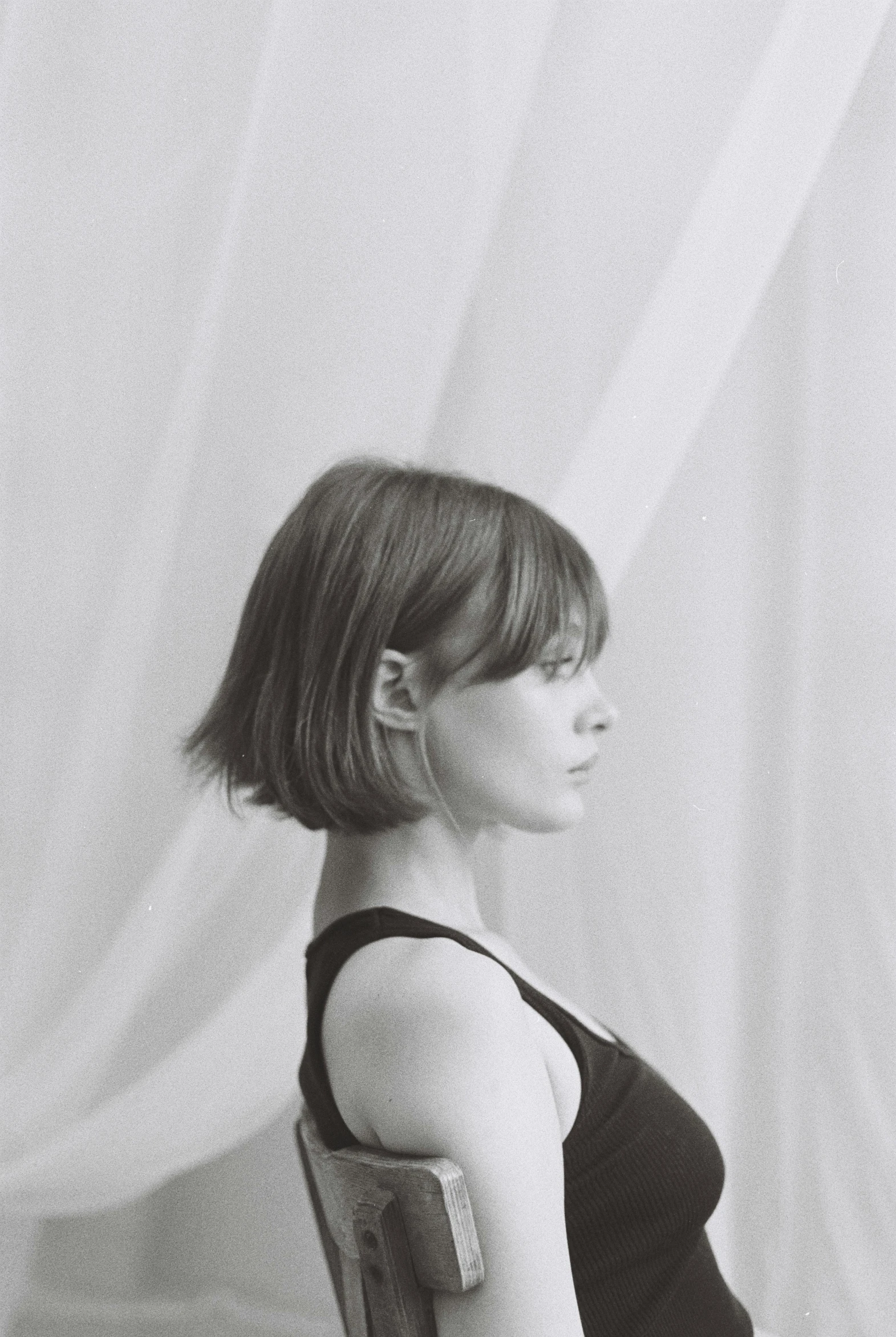 a black and white photo of a woman sitting in a chair, a black and white photo, unsplash, renaissance, side fringe haircut, aurora aksnes and zendaya, short bob hair, profile image