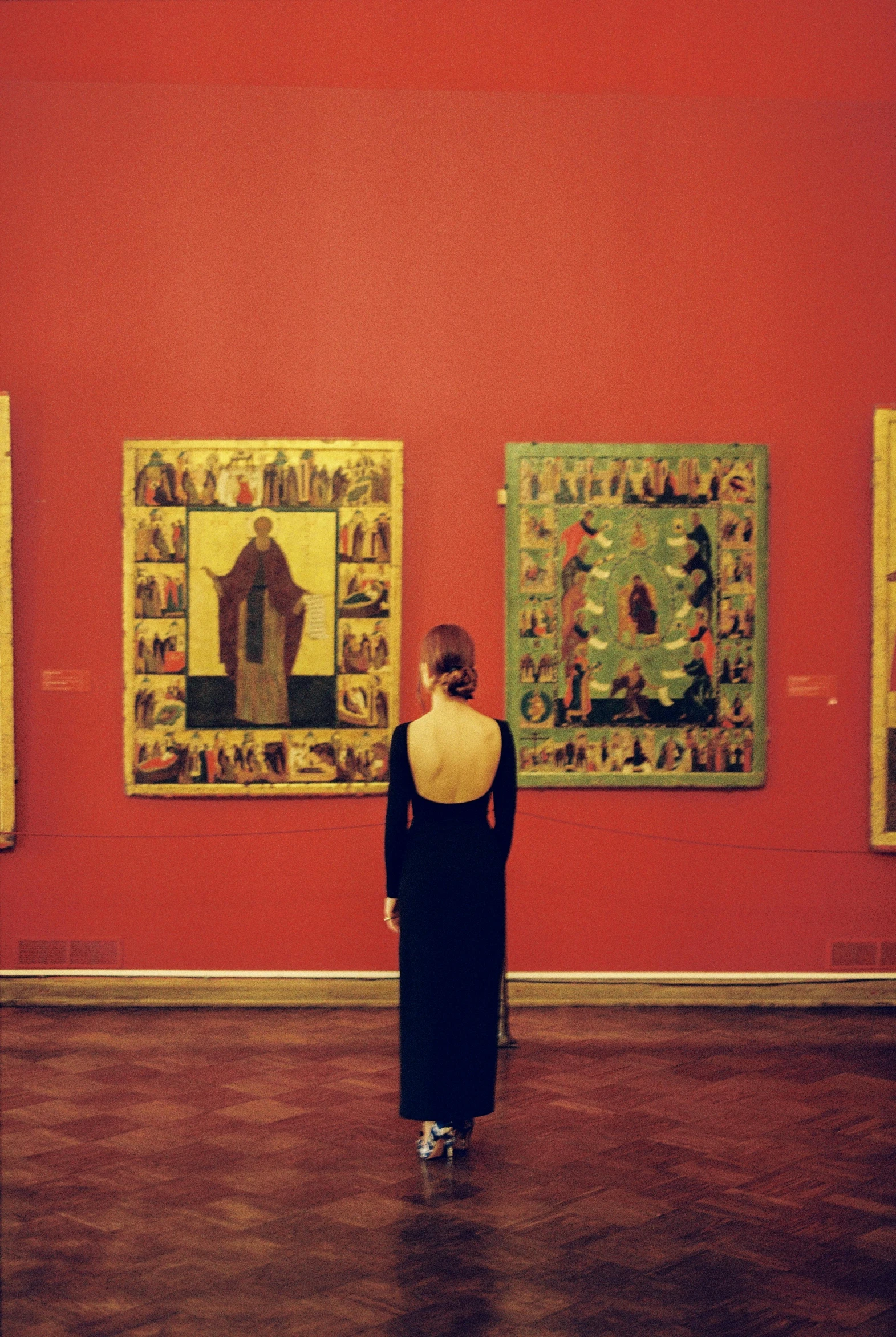 a woman standing in an art gallery looking at paintings, an album cover, inspired by Mikhail Nesterov, pexels contest winner, qajar art, facing away, orthodox icons, square, magnum photos