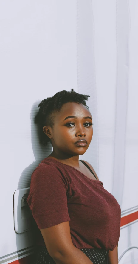 a woman leaning against a wall in front of a camper, by Lily Delissa Joseph, sitting on a mocha-colored table, looking serious, ☁🌪🌙👩🏾, headshot profile picture