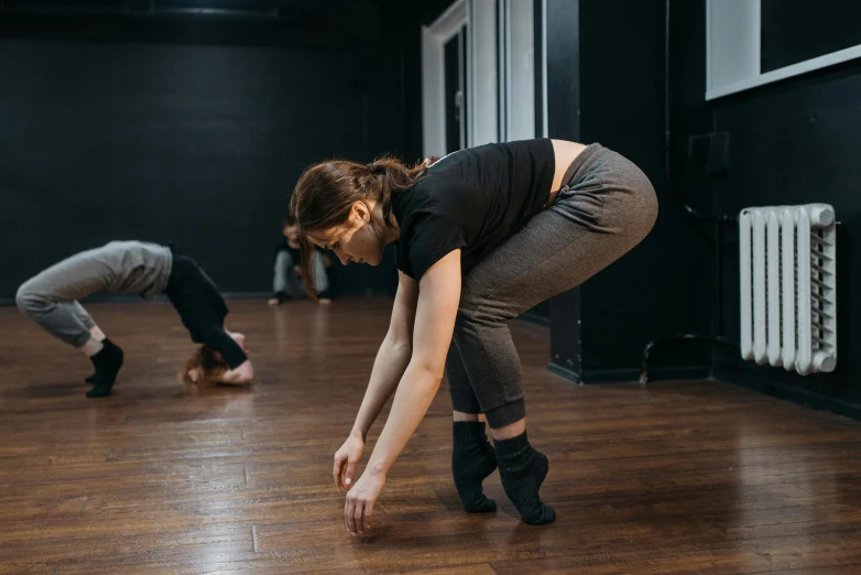 a couple of women standing on top of a wooden floor, unsplash, arabesque, performance, sydney hanson, as well as scratches, profile image