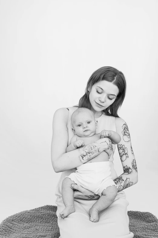 a black and white photo of a woman holding a baby, a black and white photo, by Romain brook, tattooed, aurora aksnes, with a white background, kid a