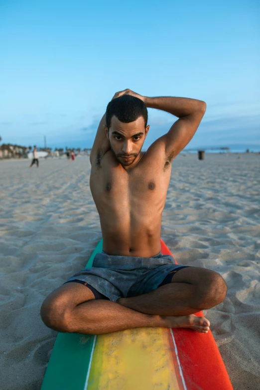 a man sitting on top of a surfboard on a beach, trending on unsplash, renaissance, non binary model, physical : tinyest midriff ever, arab man, symmetrical pose