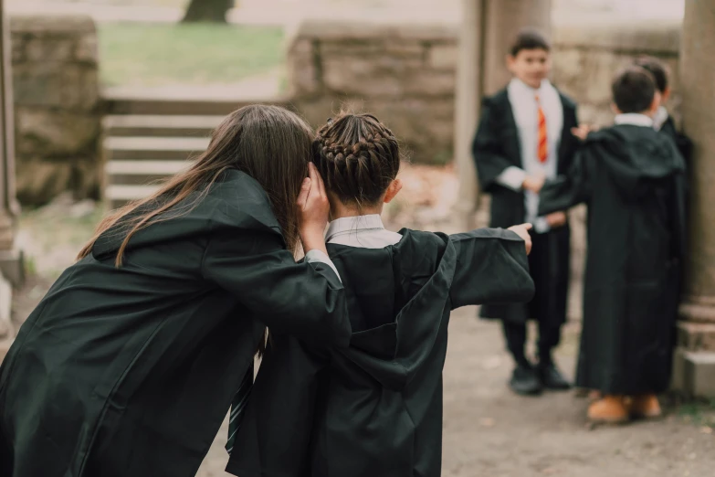 a couple of people standing next to each other, by Fuller Potter, pexels contest winner, happening, wearing an academic gown, mischief managed, boys, half turned around