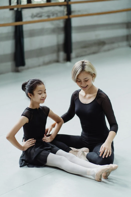 a woman sitting on the floor next to a little girl, inspired by Fei Danxu, pexels contest winner, arabesque, wearing leotard, black, teaching, square