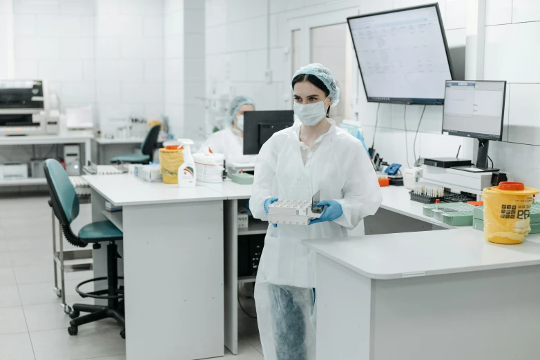 a woman in a lab coat standing in front of a counter, by Adam Marczyński, pexels contest winner, engineering bay, sterile minimalistic room, yulia nevskaya, thumbnail