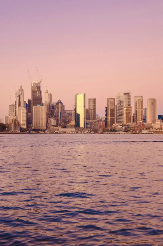 a large body of water with a city in the background, inspired by Sydney Carline, pexels contest winner, happening, pink golden hour, 3 5 mm slide, skyscapers, view from the sea