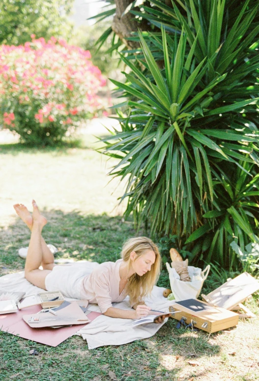 a woman laying in the grass reading a book, by Lucette Barker, happening, lourmarin, lush chic garden, studious, julia sarda