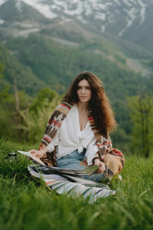 a woman sitting on top of a lush green field, an album cover, pexels contest winner, renaissance, long curly brown hair, in the mountains, shohreh aghdashloo, marina federovna