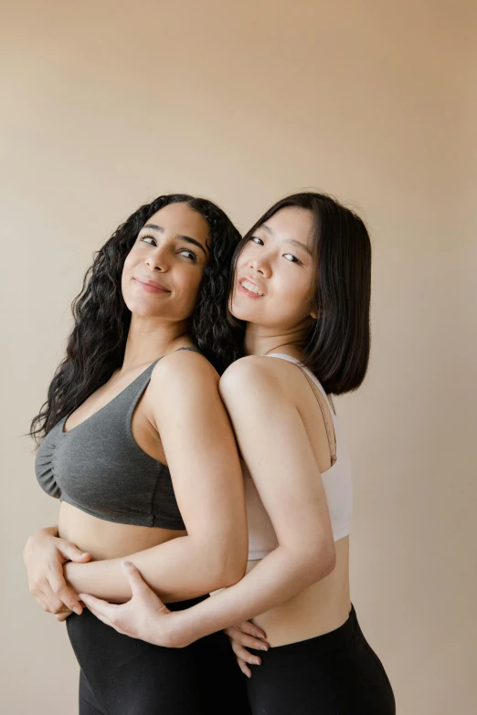 a couple of women standing next to each other, inspired by Wang Duo, trending on pexels, posing together in bra, queer, cuddling, inuit