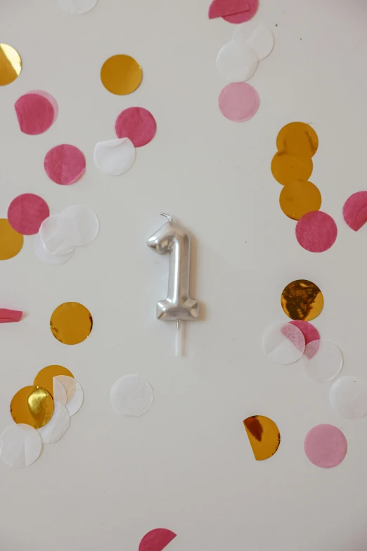 a white clock sitting on top of a table covered in confetti, wearing the number 1 headband, thumbnail, candle, small