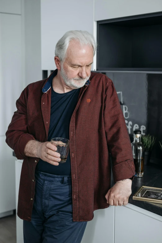 a man standing in a kitchen holding a glass, a portrait, unsplash, photorealism, dark grey haired man, cardigan, whisky, red shirt brown pants