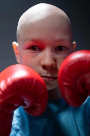 a close up of a person wearing boxing gloves, by Harriet Zeitlin, shutterstock contest winner, boy with neutral face, tumors, award winning color photo, bald