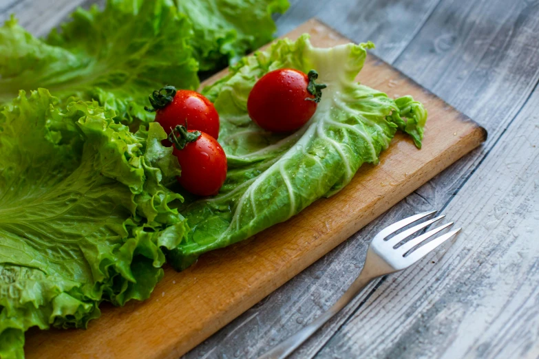 a wooden cutting board topped with lettuce and cherry tomatoes, avatar image, eating, features, medium