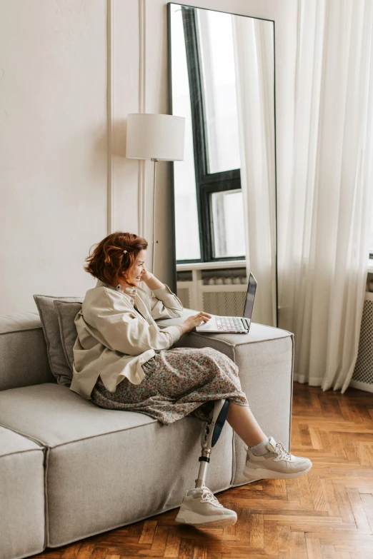 a woman sitting on a couch using a laptop, by Adam Marczyński, trending on pexels, a redheaded young woman, wide full body, city apartment cozy calm, 15081959 21121991 01012000 4k