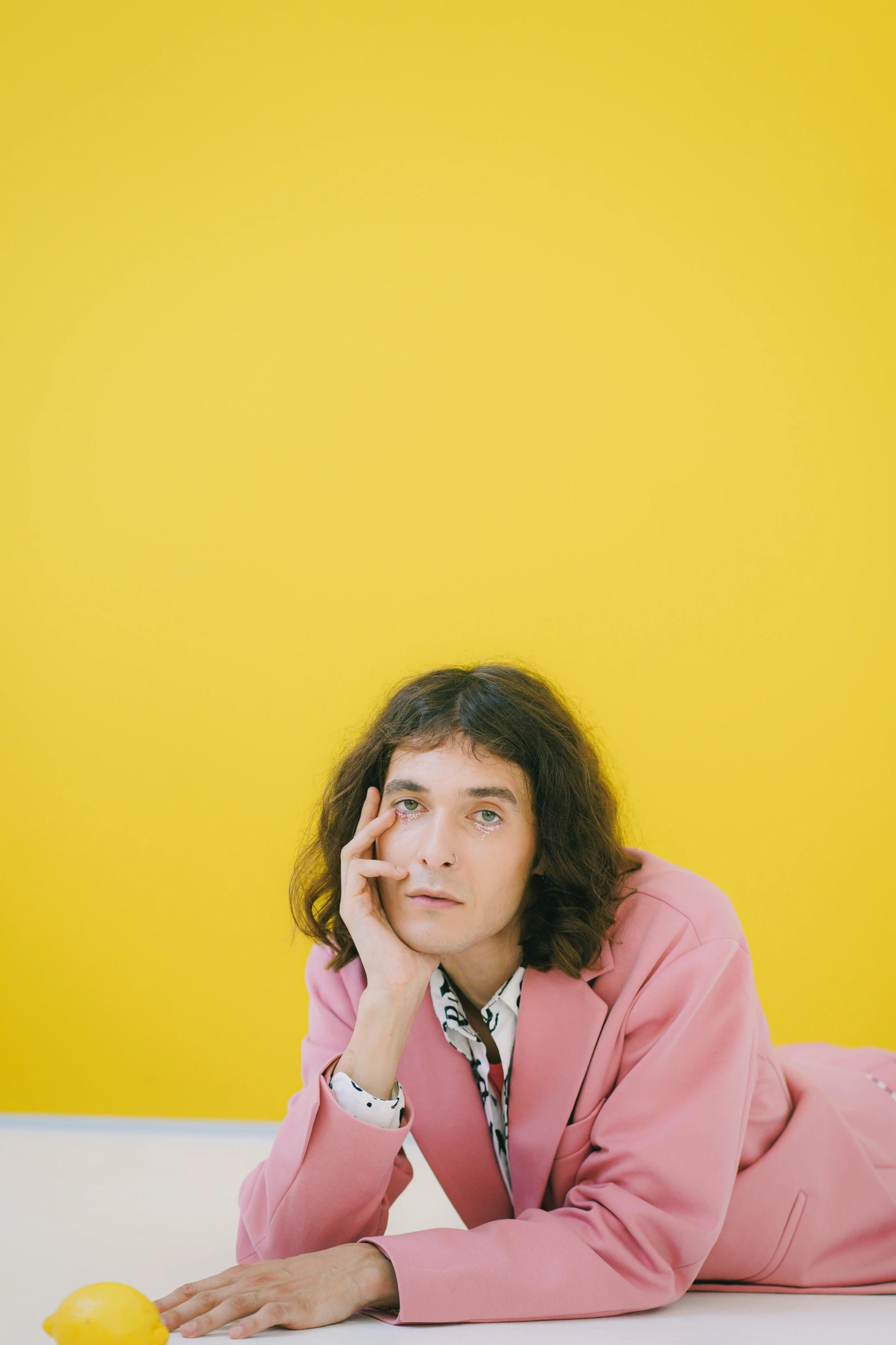 a woman laying on the floor next to a lemon, an album cover, wearing a light - pink suit, robert sheehan, matt mute colour background, photographed on colour film