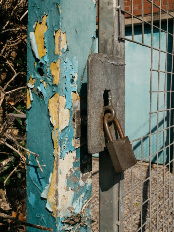 a close up of a fence with a padlock on it, by Elsa Bleda, brown and cyan color scheme, building crumbling, background image, schools