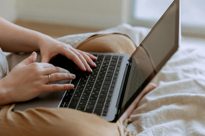 a woman sitting on a bed using a laptop computer, trending on pexels, close up to the screen, brown, rounded lines, laying down