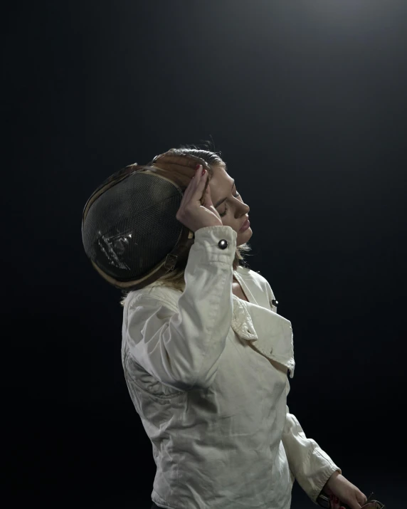 a woman standing on a tennis court holding a racquet, inspired by Graham Forsythe, light and space, clothed in space suit, holding his hands up to his face, showstudio, wearing a round helmet