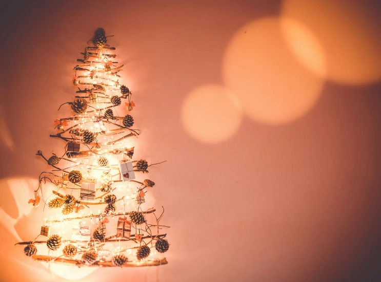 a small christmas tree sitting on top of a table, pexels, light and space, string lights, background image, retro stylised, ivory and copper