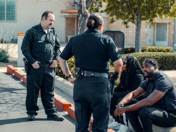 a group of men sitting on the side of a road, kim kardashian as a cop, standing in a parking lot, getty images proshot, customers