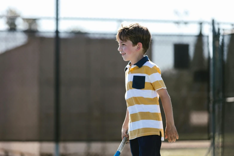 a young boy holding a tennis racquet on a tennis court, unsplash, american barbizon school, wearing polo shirt, gold, 15081959 21121991 01012000 4k, mini model