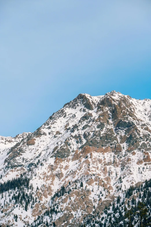 a man riding a snowboard on top of a snow covered mountain, a photo, trending on unsplash, minimalism, large rocky mountain, hill with trees, in the swiss alps, slightly pixelated