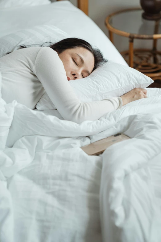 a woman is sleeping in a white bed, wearing a white sweater, an asian woman, premium, multiple stories