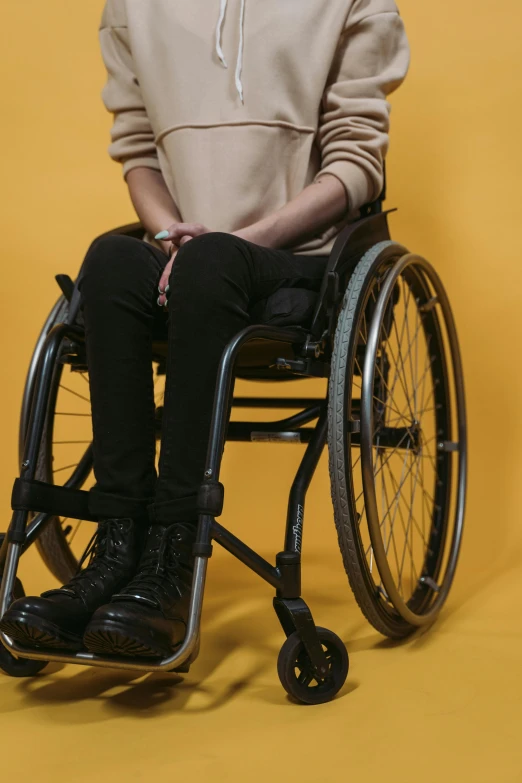 a man sitting in a wheelchair on a yellow background, by Adam Marczyński, trending on pexels, panoramic view of girl, stitches, standing with a black background, mid body shot