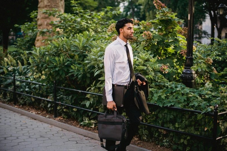 a man walking down a sidewalk carrying a suit case, pexels contest winner, renaissance, central park, wearing a white button up shirt, over the shoulder, working