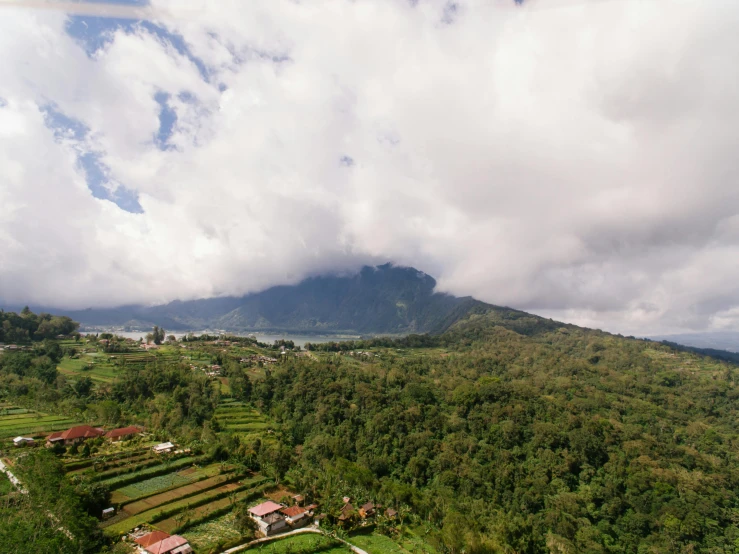 a bird's eye view of a lush green valley, pexels contest winner, sumatraism, towering cumulonimbus clouds, temple in the distance, hd footage, coban