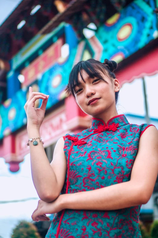 a woman standing in front of a colorful building, inspired by Mei Qing, pexels contest winner, symbolism, young cute wan asian face, red and cyan, cheongsam, 8k artgerm bokeh