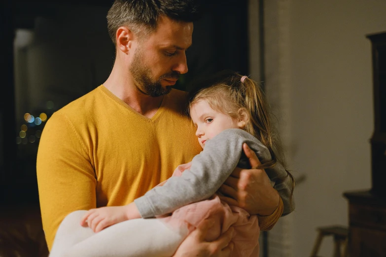 a man holding a little girl in his arms, pexels, avatar image, looking sad, gif, standing in a dimly lit room