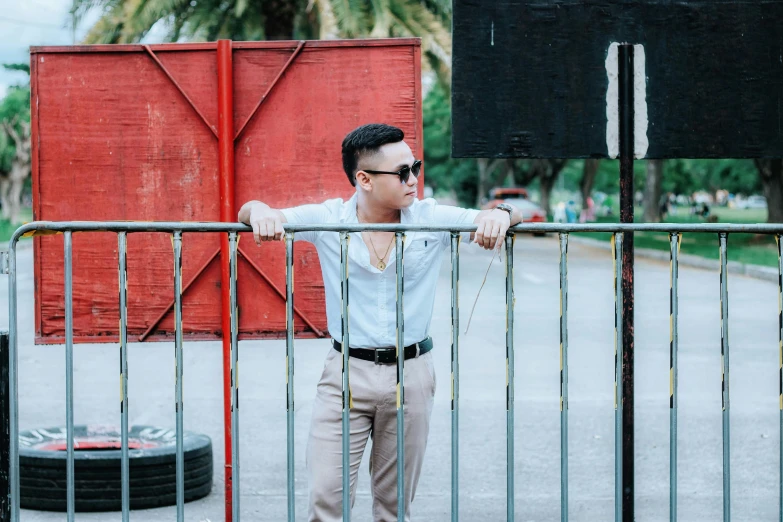 a man standing next to a metal fence, unsplash, happening, in style of lam manh, mid-twenties, background image, square