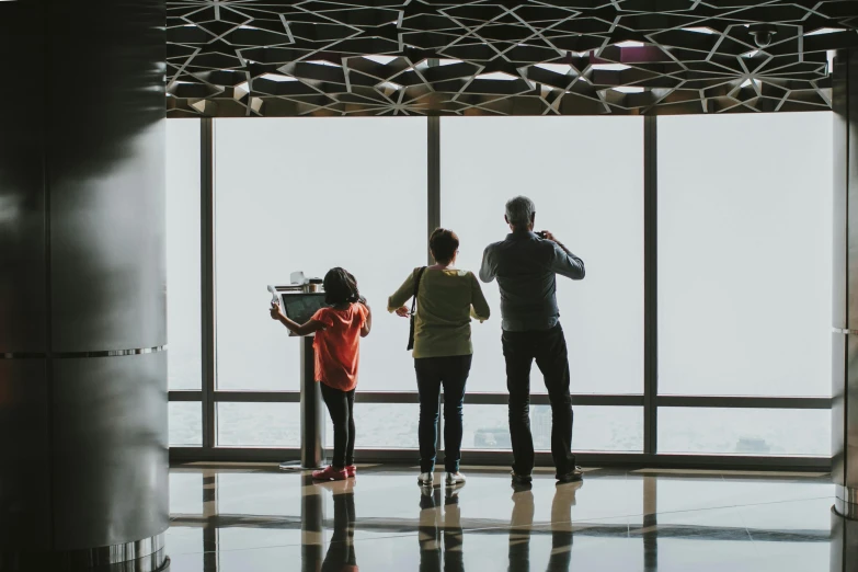 a group of people standing in front of a window, by Lee Loughridge, pexels contest winner, visual art, observation deck, families playing, standing in a large empty hall, skyline showing