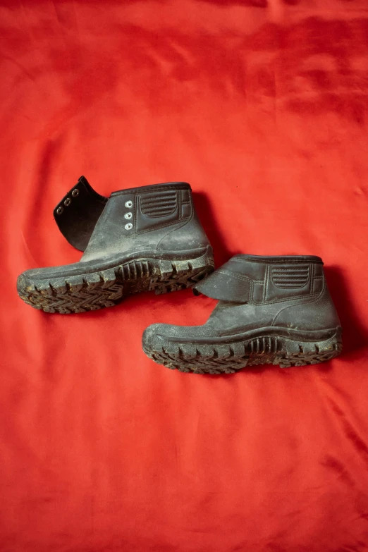 a pair of shoes sitting on top of a red sheet, heavy-duty boots, slide show, more, muddy