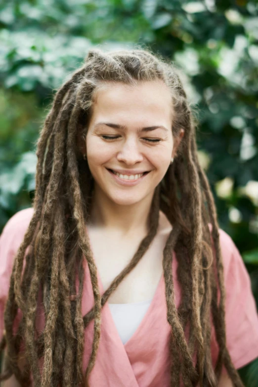 a woman with dreadlocks smiles at the camera, meditative, profile image, multiple stories, mixed race