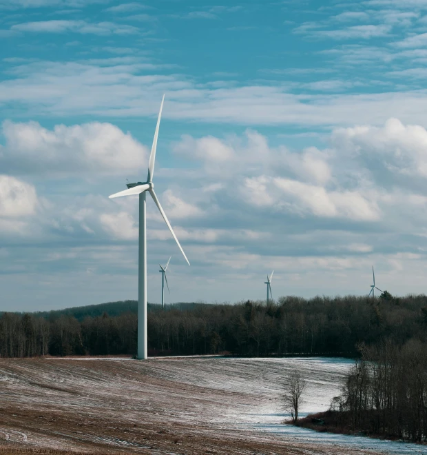 a group of wind turbines sitting on top of a snow covered field