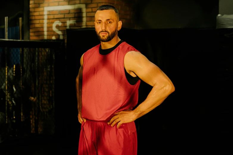 a man standing with his hands on his hips, inspired by Jordan Grimmer, dribble, red vest, in a boxing ring, press shot, elias chatzoudis