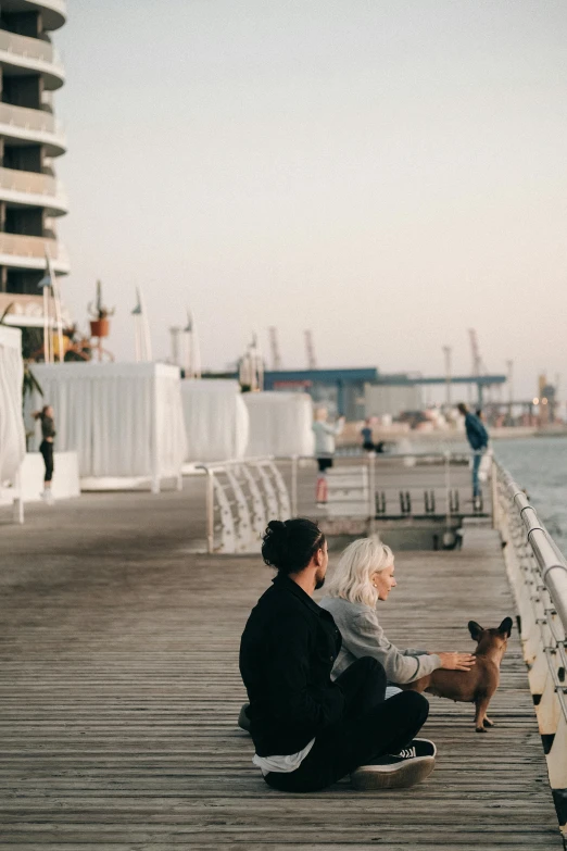 a man and woman sitting on a pier with a dog, pexels contest winner, romanticism, melbourne, unfinished, brown, cozy setting