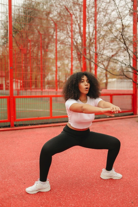 a woman standing on a tennis court holding a tennis racquet, an album cover, pexels contest winner, arabesque, squatting pose, curvy crossfit build, with afro, 15081959 21121991 01012000 4k