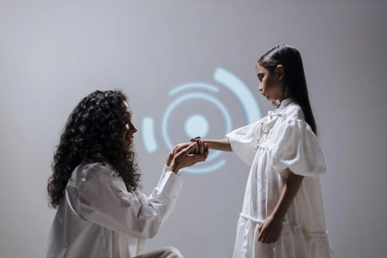 a woman putting a ring on another woman's finger, a hologram, inspired by Anna Füssli, interactive art, girl in white dress dancing, smart textiles, ameera al-taweel, press shot